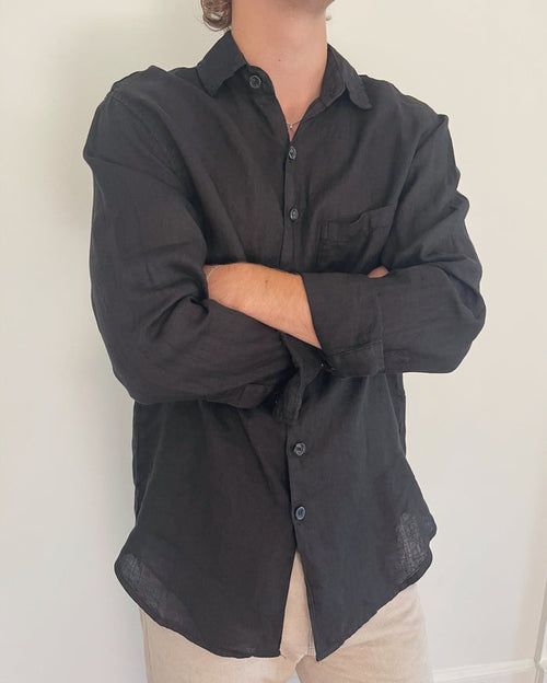 Model wearing Two Sons black linen button down shirt with arms crossed, styled with beige trousers