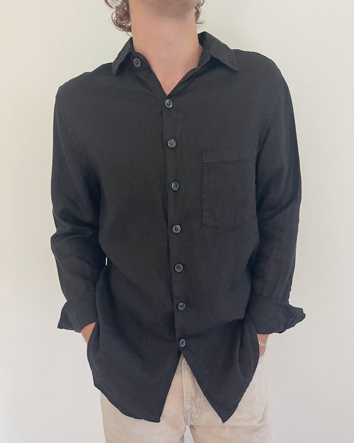 Model wearing Two Sons black linen button down shirt, hands in pockets, styled with beige trousers