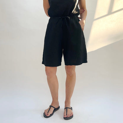 Person wearing a black sleeveless top and shorts on a white background