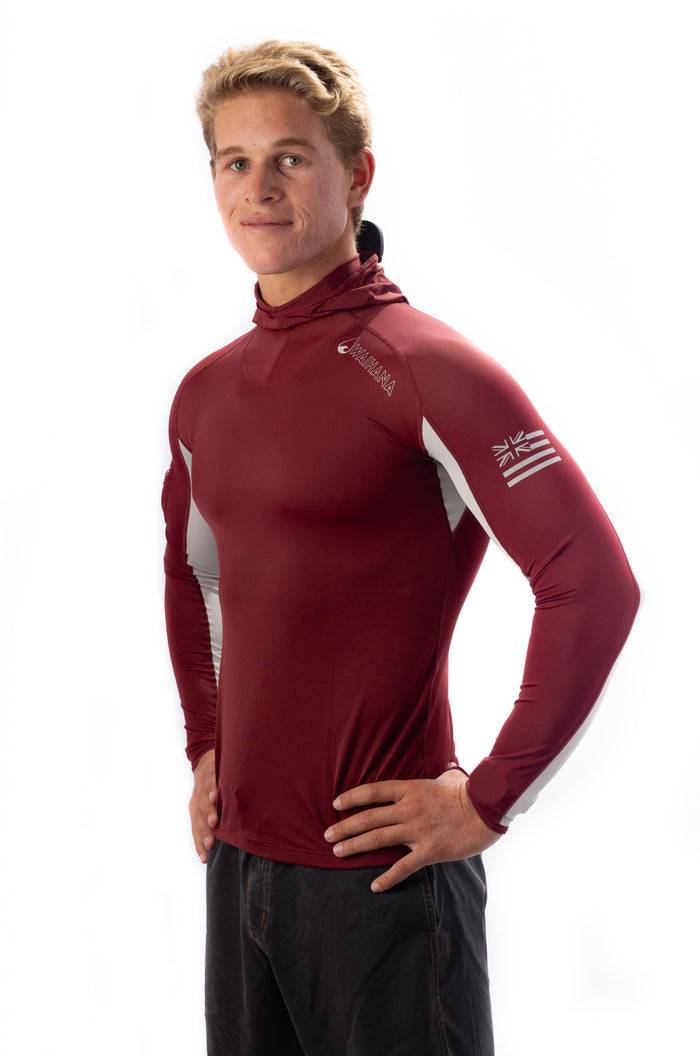 Male model wearing a maroon Waihana Carvico hooded long-sleeve surf rashguard with white side panels and Hawaiian flag sleeve detail, posed at a three-quarter angle against a white background.