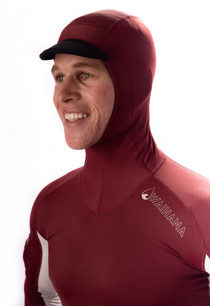 Smiling man wearing a maroon Waihana hooded surf rashguard with an integrated black brim cap, shown from the chest up against a white background.
