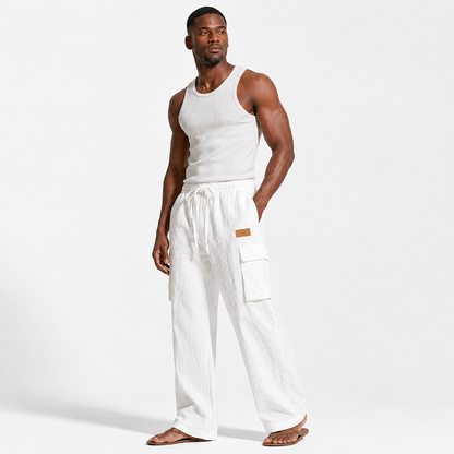 Men's cotton linen pants in white shown at a three-quarter angle on an adult male model with pockets and drawstring visible.