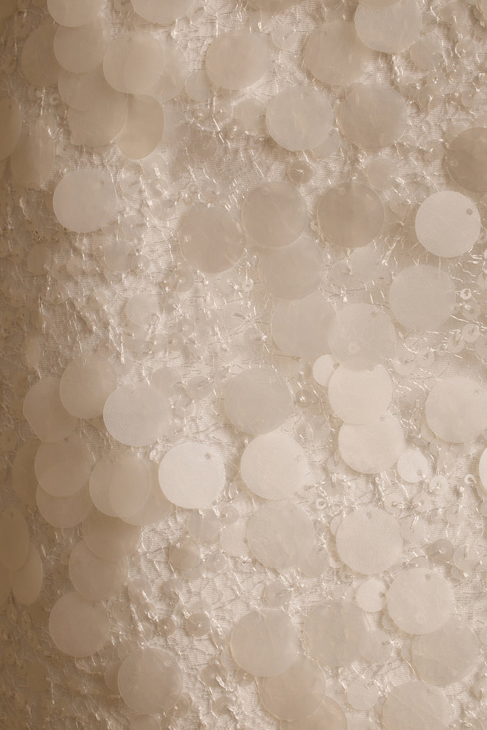 Close-up of white payette sequin discs stitched across the Miramar mini skirt fabric.