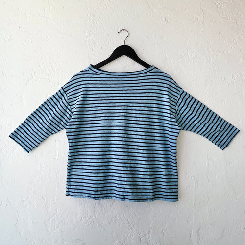 Blue and white striped shirt on a hanger against a white wall