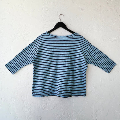 Blue and white striped shirt on a hanger against a white wall