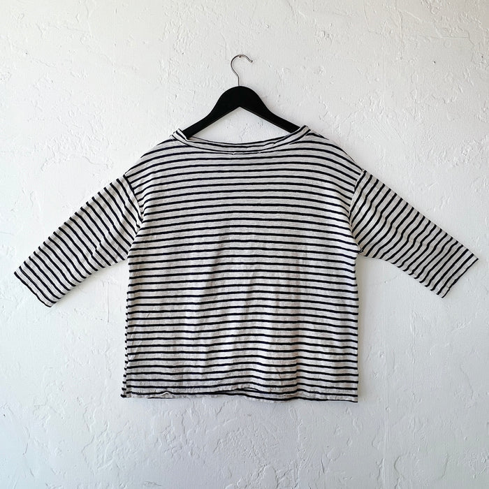 Navy and white striped shirt on a hanger against a white wall, viewed from behind