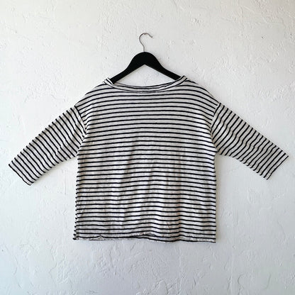 Navy and white striped shirt on a hanger against a white wall, viewed from behind