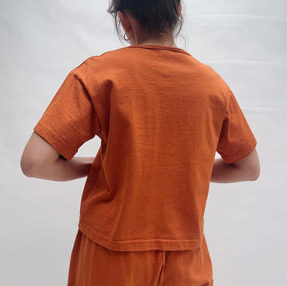 Person wearing an orange outfit against a white background, viewed from the back