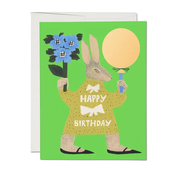 A greeting card with an illustration of a cartoon rabbit wearing a party hat and holding a balloon, with the text 'Happy Birthday' and a blue flower. The background is green.