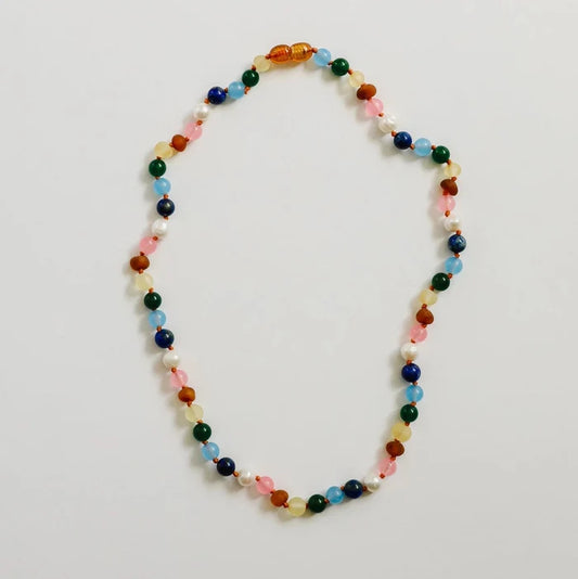 CanyonLeaf Raw Baltic Amber and Pearl + Multi Colored Gemstones Necklace — a hand-knotted necklace alternating raw honey amber, white pearl, pink rose quartz, blue aquamarine, navy lapis, green jade, and yellow amber beads with a honey amber screw clasp, laid flat on a light grey background