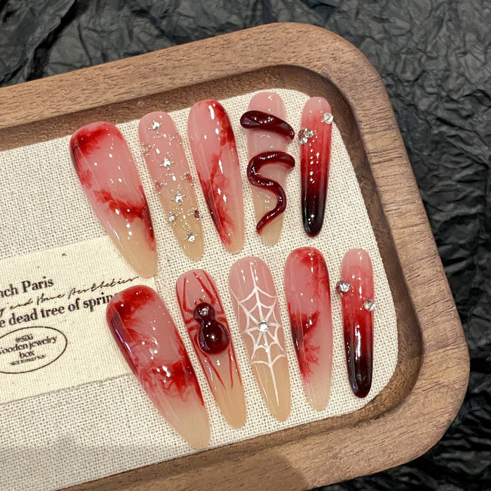 Long red press-on nails with glossy cat's eye shimmer and statement motifs, displayed with the included application tool kit.