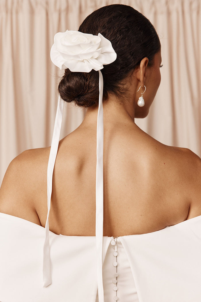 Woman wearing a white floral bridal hairpiece