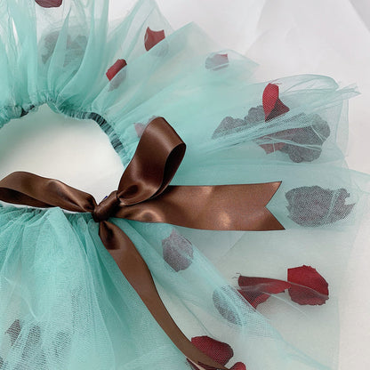 Close-up of the brown bow of the green mesh material of the tutu and dark red petals