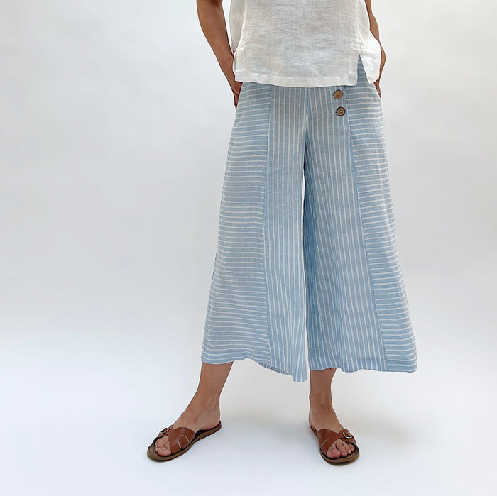Person wearing light blue striped wide-leg pants with a white top on a white background