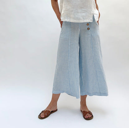 Person wearing light blue striped wide-leg pants with a white top on a white background