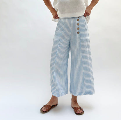 Person wearing light blue striped pants with button details on a white background