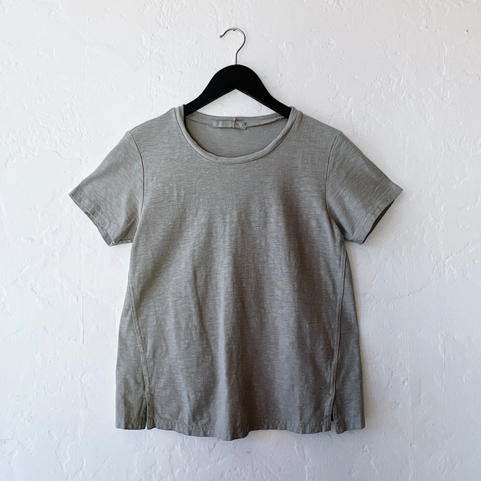 Green t-shirt on a hanger against a white wall