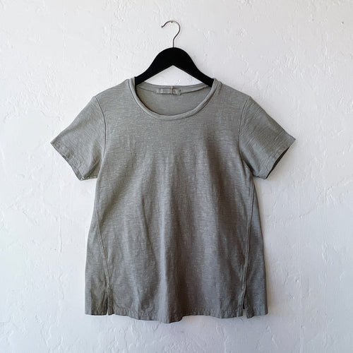 Green t-shirt on a hanger against a white wall
