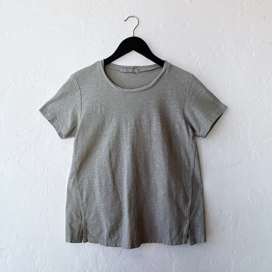 Green t-shirt on a hanger against a white wall