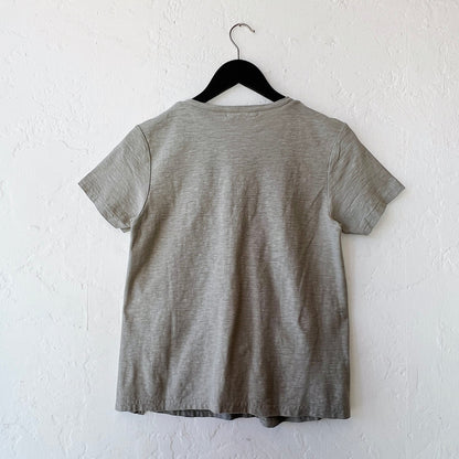 Green t-shirt on a hanger against a white wall, viewed from behind