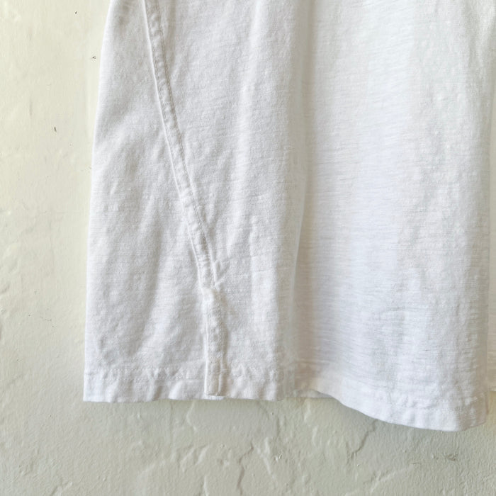 Close up of white t-shirt fabric photographed against a white wall.