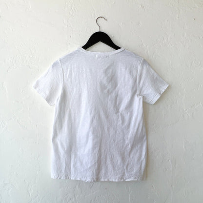 White t-shirt on a black hanger against a white wall