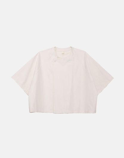 Off-white minimalist short sleeve shirt with wide, boxy silhouette and subtle asymmetrical front detail, crafted for understated elegance and comfortable movement.