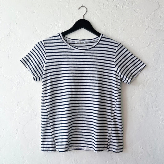 A striped navy and white short sleeve tee with slit hem, displayed on a hanger against a white wall.