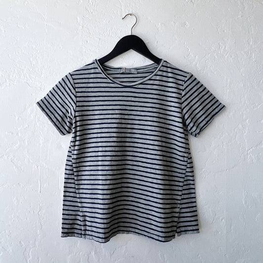 Gray and black striped t-shirt on a hanger against a white wall
