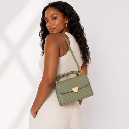 Sage green quilted heart-clasp shoulder bag worn by a professional Black woman model in a rear three-quarter studio view.