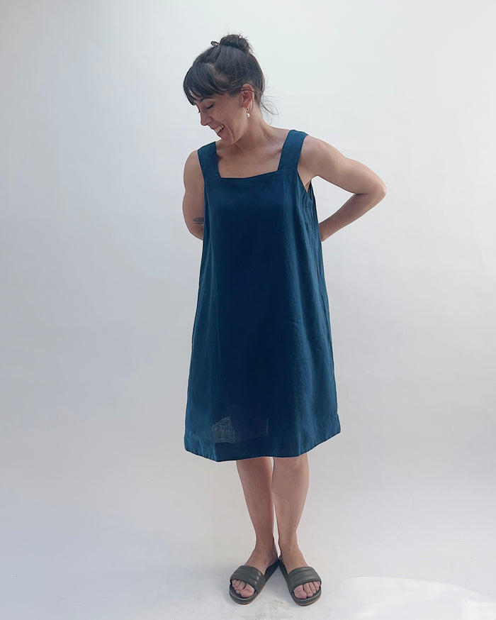 Woman wearing a dark blue sleeveless dress against a white background