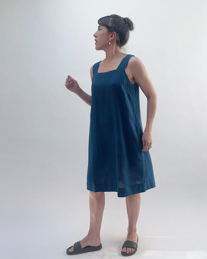 Woman wearing a blue sleeveless dress against a white background