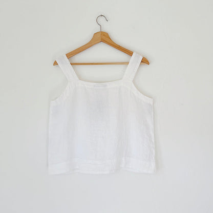 White tank top on a wooden hanger against a white background, viewed from the back
