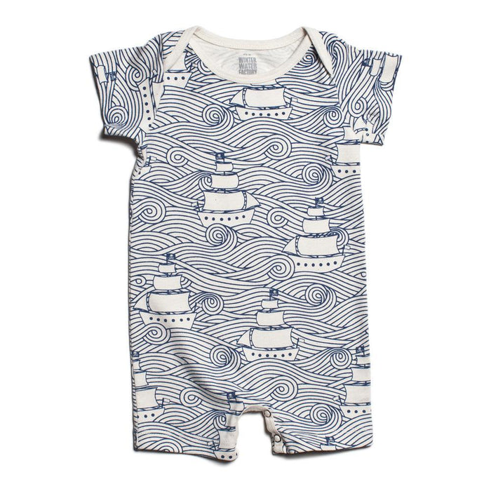 A short-sleeved romper with a high seas wave and ship pattern, including snap buttons for closure.