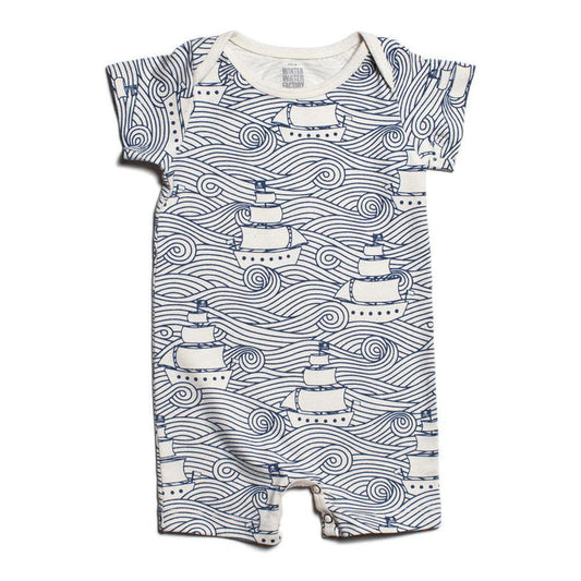 A short-sleeved romper with a high seas wave and ship pattern, including snap buttons for closure.