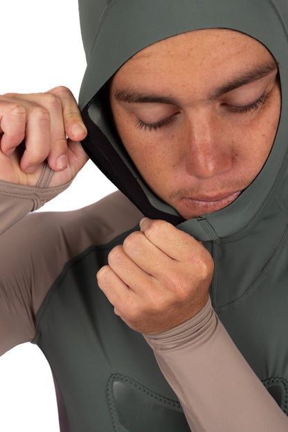 Male model pulling the fitted hood of the Waihana Terra Hooded Spearfishing Rashguard over his face, highlighting the structured hood opening and taupe sleeve against a white studio background.