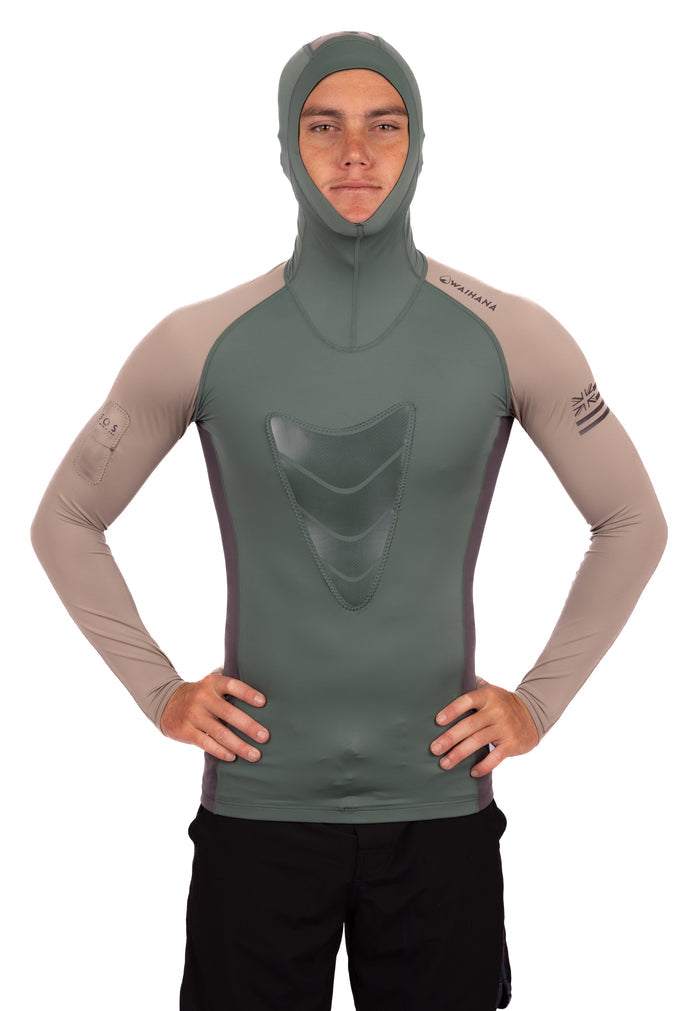 Male model wearing the Waihana Terra Hooded Spearfishing Rashguard in olive green and sand tan, featuring a chest load pad, integrated hood, and Hawaiian flag sleeve detail, photographed front-on against a white background.