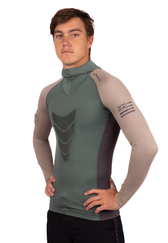 Male model wearing the Waihana Terra Hooded Spearfishing Rashguard in sage green and tan colorblocking with a chest shield panel, mock neck, and Hawaiian flag graphic on the left sleeve, shown from a three-quarter side angle against a white background.