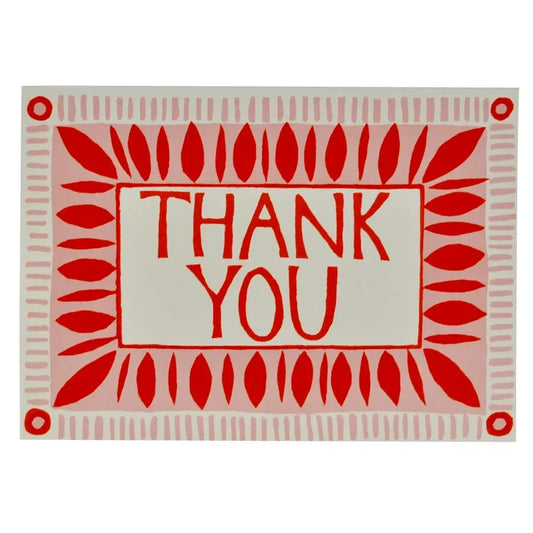 A greeting card with a pink background and red text that reads 'THANK YOU' in a circular pattern around the center. The card has a smooth, uncoated stock texture and is blank inside.