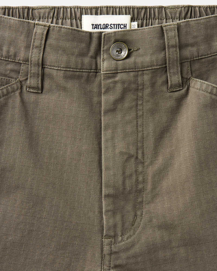 Close-up of a brown pants pocket with a button and Taylor Stitch label.