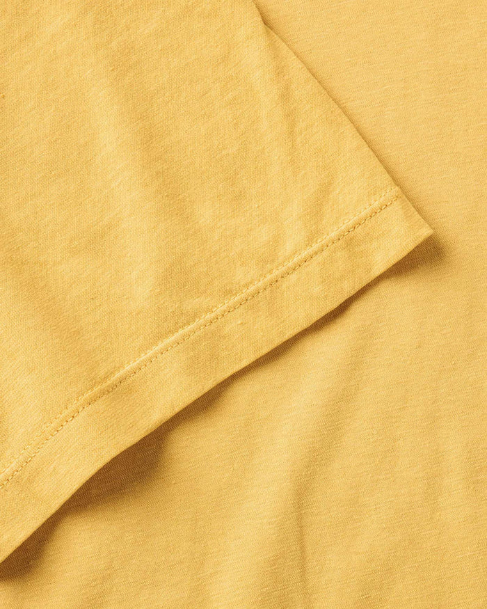 Close-up detail of Taylor Stitch Cotton Hemp Tee sleeve hem showing stitching and soft organic cotton fabric texture in Goldfinch yellow