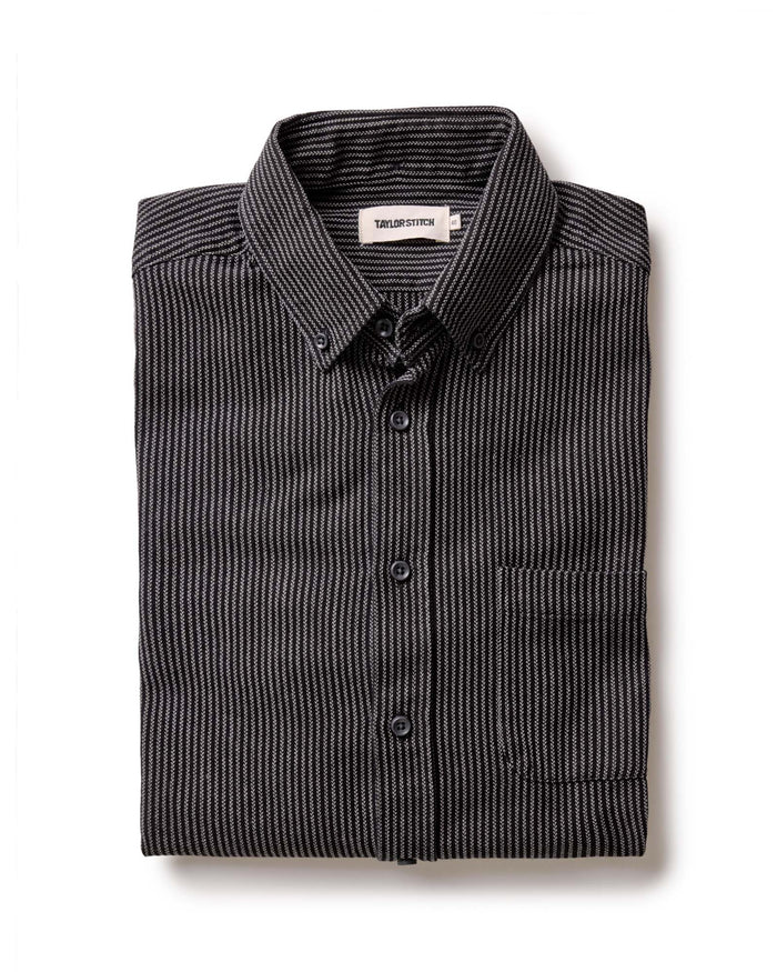 The Jack in Roped Black Indigo by Taylor Stitch, folded flat lay showing roped indigo stripe texture, button-down collar, and chest pocket with Taylor Stitch label