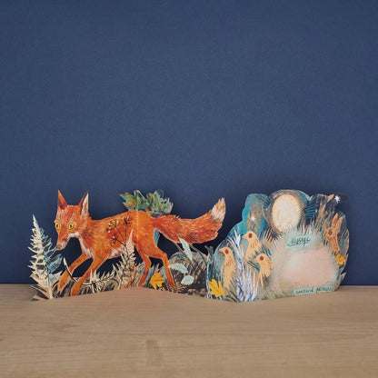 Three Fold Fox concertina card open to reveal blank message panel surrounded by illustrated birds and a hare under moonlight, with fox and fern foliage on the front panel, signed by Mark Hearld and Art Angels
