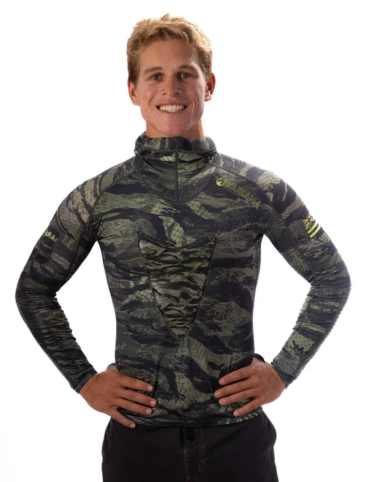 Smiling male model wearing the Waihana Tropicam Hooded Spearfishing Rashguard in Tropicam Green camouflage pattern, hands on hips, studio white background.