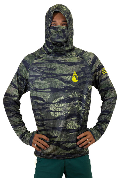 Male model wearing the Waihana Tropicam Sun Shirt in green and black camouflage pattern with attached hood and face mask pulled up, yellow Waihana brand logo on the chest, hands on hips against a white studio background.