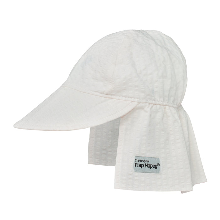 A white sun hat with a large brim and an elastic band, featuring a vanilla stripe pattern and a label that says 'Flap Happy.'