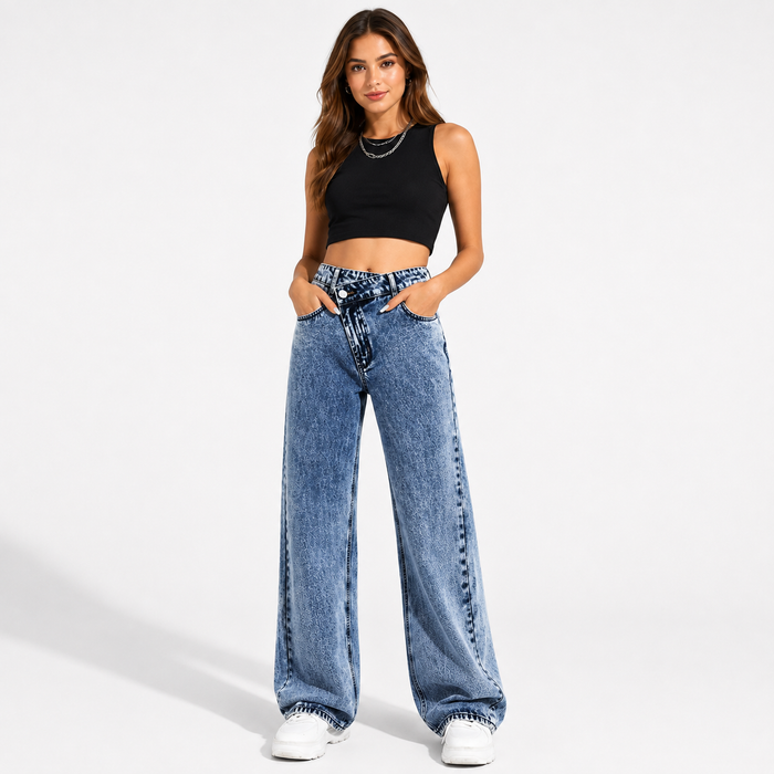 Women's high waisted wide leg jeans in medium blue wash with crossover waist, front view with hands in pockets.