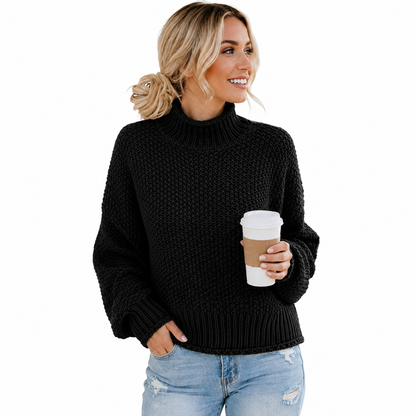 Women's black turtleneck sweater on a model holding a coffee cup, styled with jeans on a clean white studio background.